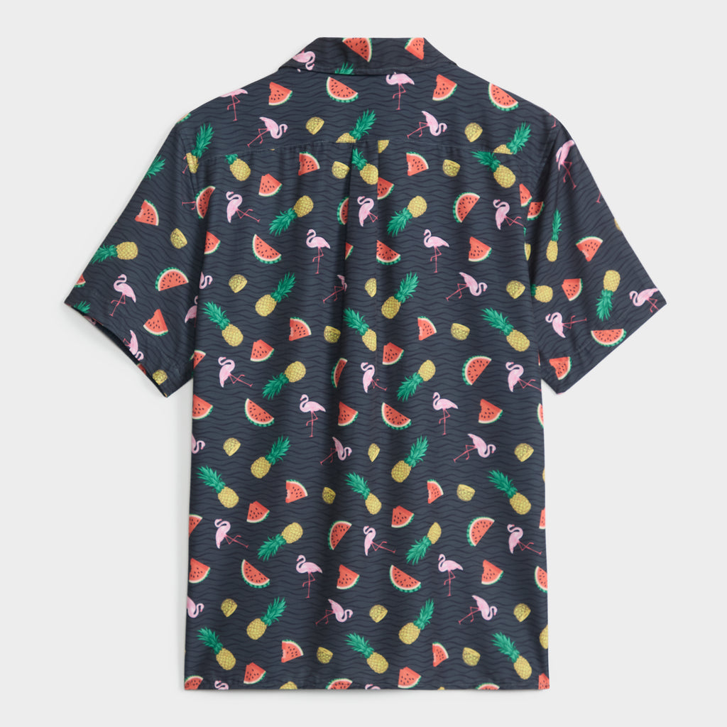 The TROPICAL TANGO SHIRT by PUBLIC BEACH SWIM is a short-sleeve, dark tropical top with pink flamingos, watermelon slices, pineapples, and palm leaves—ideal for vacation or beachwear. Shirt is shown flat with the back facing up.