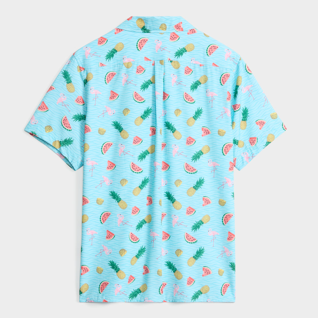 The PUBLIC BEACH SWIM TROPICAL TANGO SHIRT features short sleeves and a light blue background with pink flamingos, yellow pineapples, green palm leaves, and red watermelons. This summer shirt is displayed from the back.