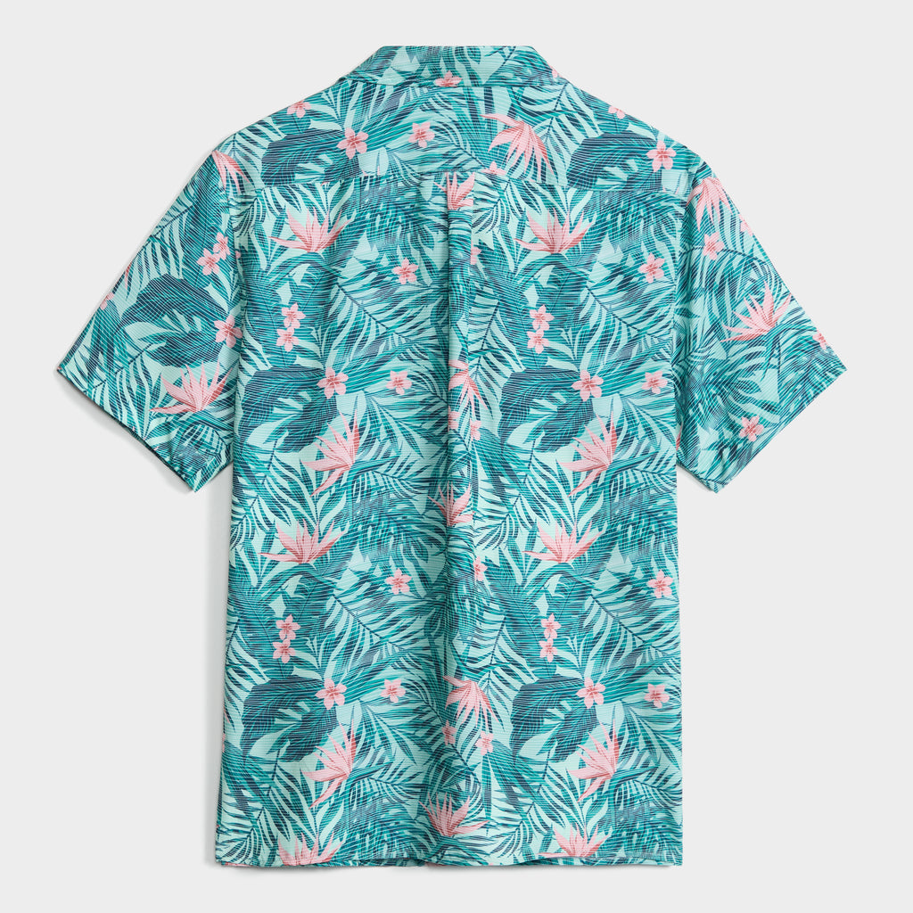 The TROPICAL PULSE SHIRT by PUBLIC BEACH SWIM features short sleeves, a Cuban collar, and a vibrant teal, white, and pink tropical leaf and flower print on airy seersucker. Shown from the back against a white background.