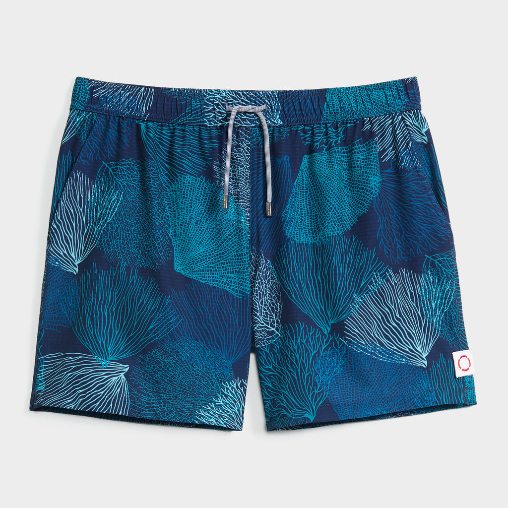 PUBLIC BEACH SWIM OCEAN BLOOM navy swim shorts feature a teal and aqua coral reef print, elastic waistband with drawstring, small white patch with red circle on the left leg, and a comfy compression liner.