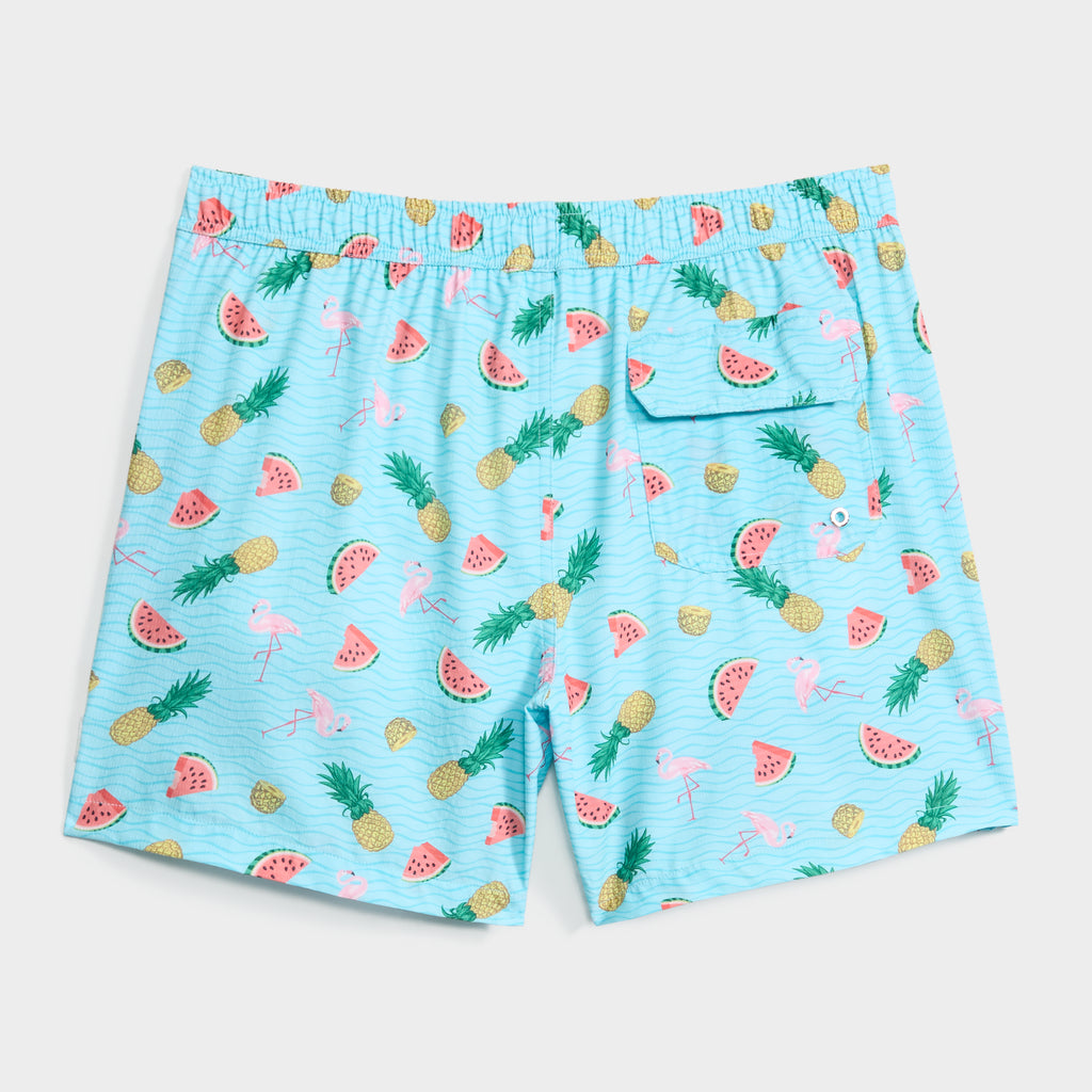 TROPICAL TANGO swim shorts by PUBLIC BEACH SWIM feature a light blue tropical print with pineapples, watermelon slices, and flamingos, plus an elastic waistband, back pocket, and supportive compression liner.