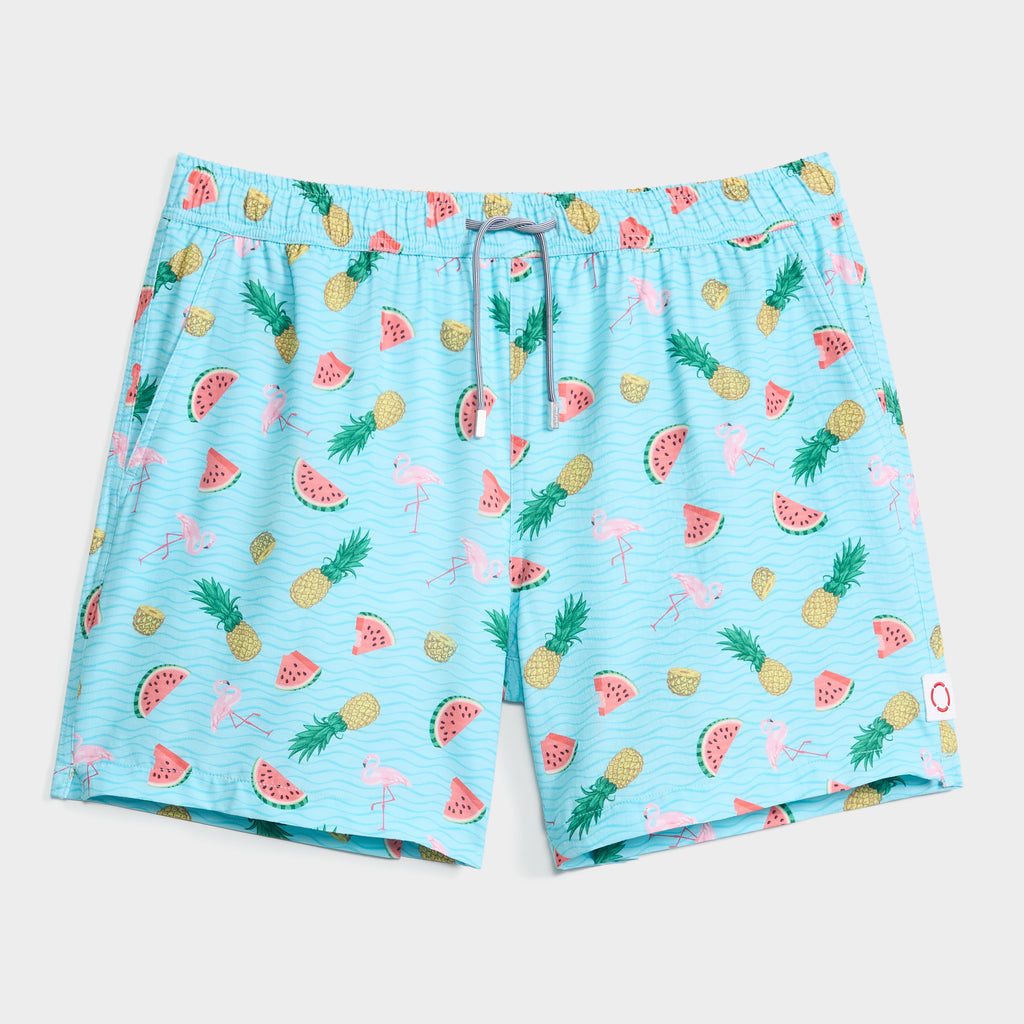 TROPICAL TANGO swim shorts by PUBLIC BEACH SWIM feature a light blue design with playful pineapples, watermelon slices, pink flamingos, and a comfy drawstring waist.