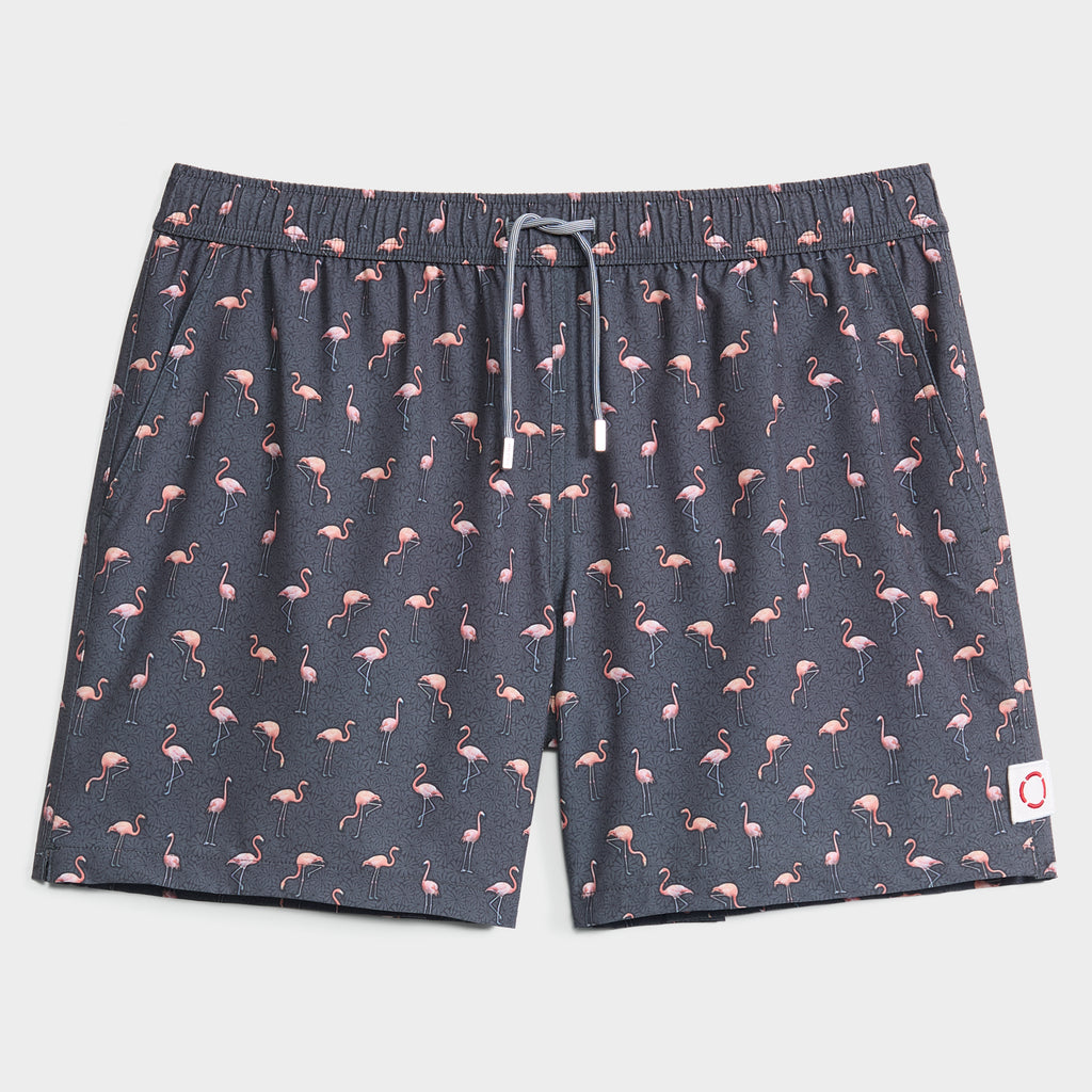 FLAMINGO VIBES swim trunks by PUBLIC BEACH SWIM feature an all-over pink flamingo print, elastic waistband, white drawstring, and a red ring logo patch—perfect quick-dry shorts for stylish beachwear lovers.