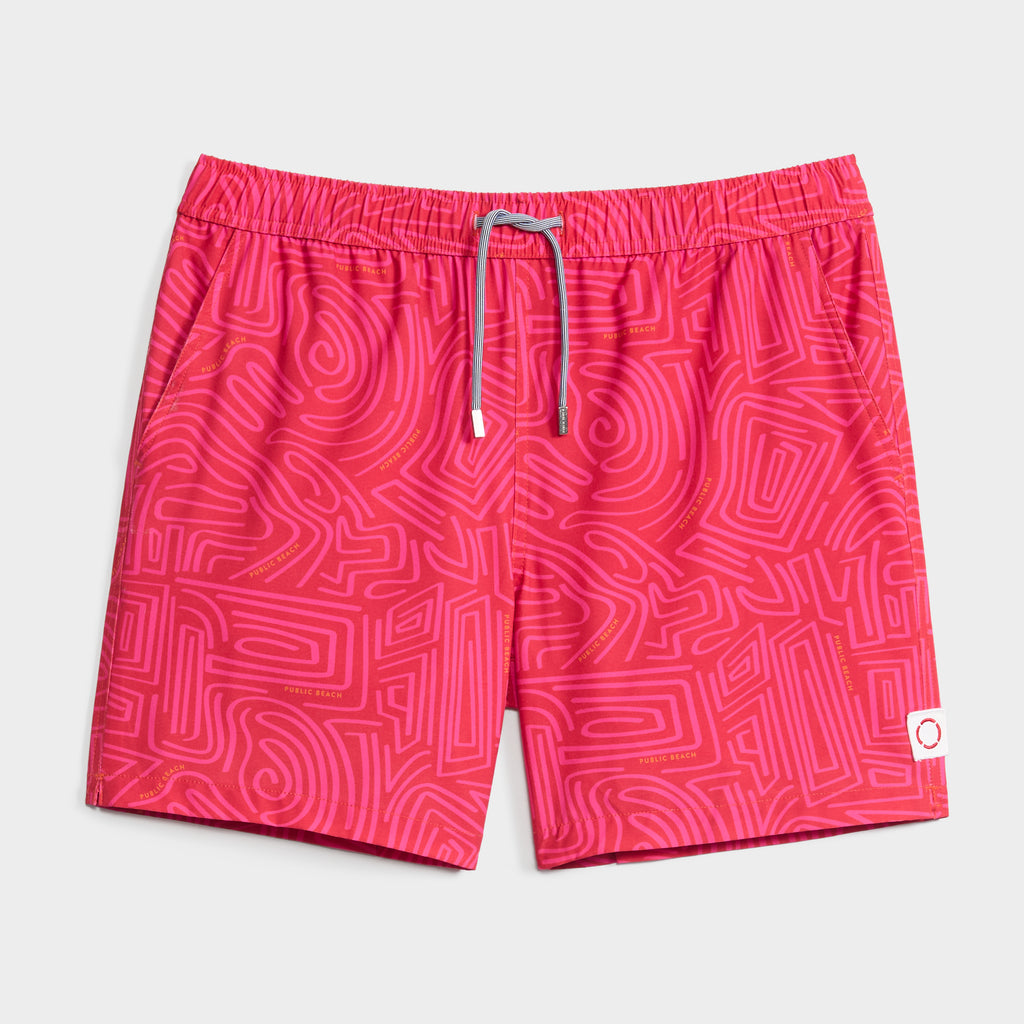 The TWISTED PATH swim shorts by PUBLIC BEACH SWIM feature a bright pink, maze-inspired print, white drawstring waistband, and a small white patch with red circle on the left leg. Crafted from quick-dry fabric.