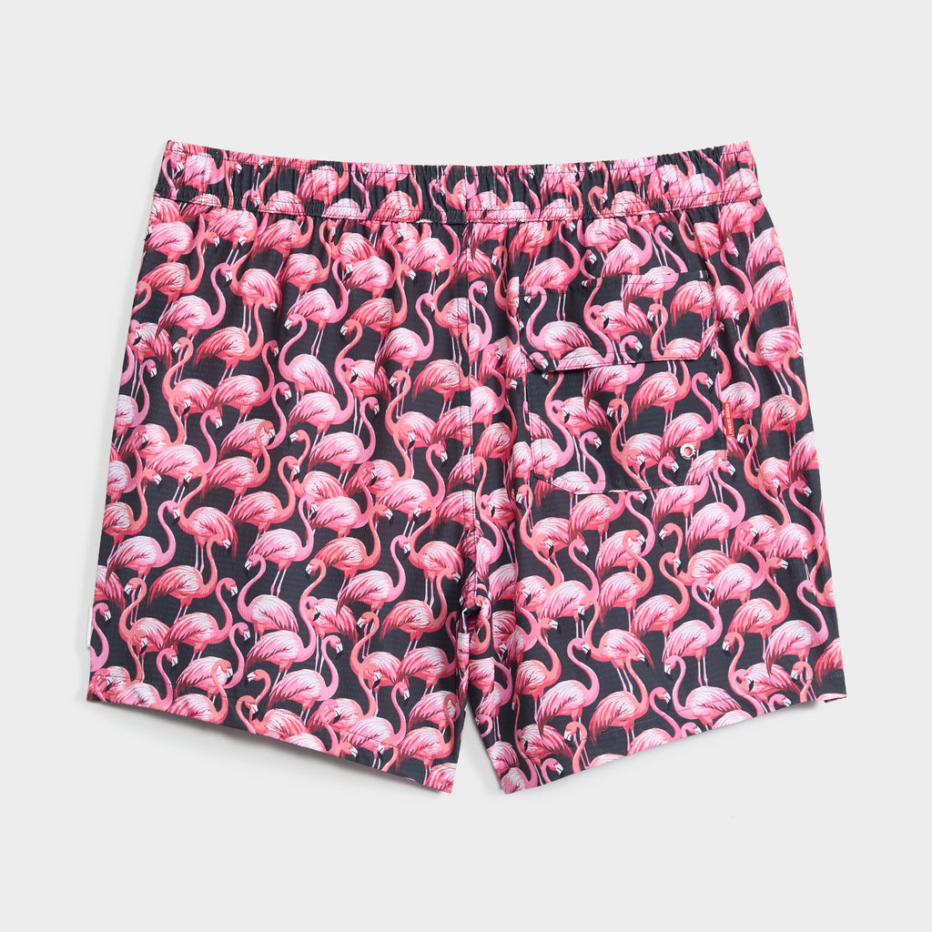 PINK MIRAGE swim trunks by PUBLIC BEACH SWIM feature quick-dry fabric, an elastic waistband, an all-over pink flamingo print on a dark background, and a convenient right-side pocket.