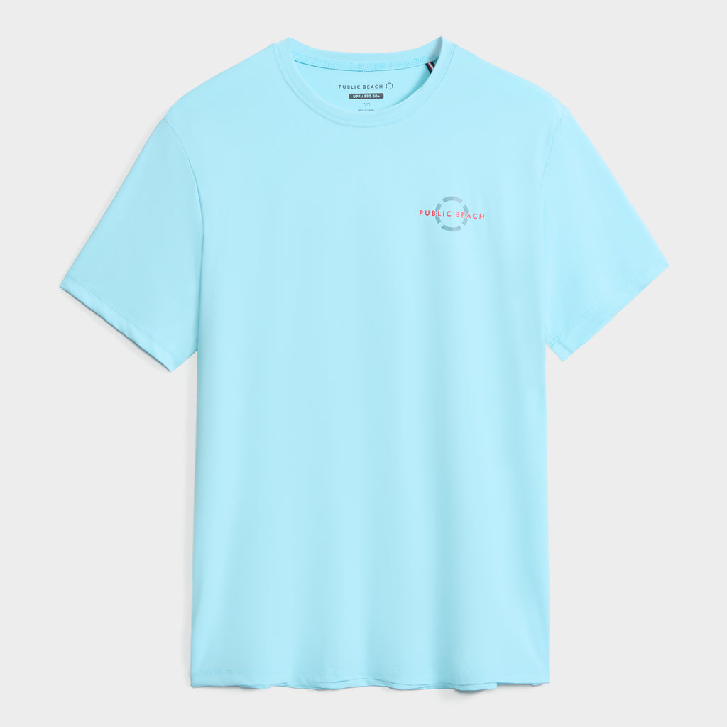 The PUBLIC BEACH SWIM SHORT SLEEVE RASHGUARD for men features a light blue color, small logo on the left chest, quick-drying fabric, and UPF 50 sun protection. Displayed flat on a white background.