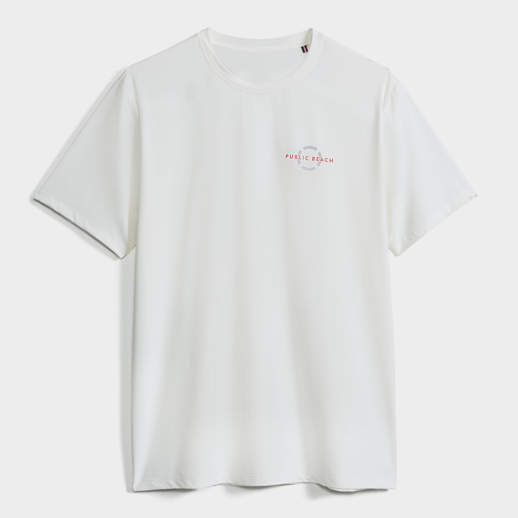 The SHORT SLEEVE RASHGUARD by PUBLIC BEACH SWIM is a plain white men's shirt with a small circular logo and "Public Beach" in red and blue on the left chest, offering UPF 50 sun protection. Displayed on a white background.