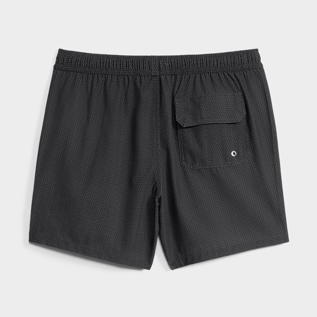 The LINK FLOW by PUBLIC BEACH SWIM are black quick-dry swim shorts featuring a subtle dot pattern, elastic waistband, and a single back pocket with flap and drainage eyelet—perfect stylish beachwear.