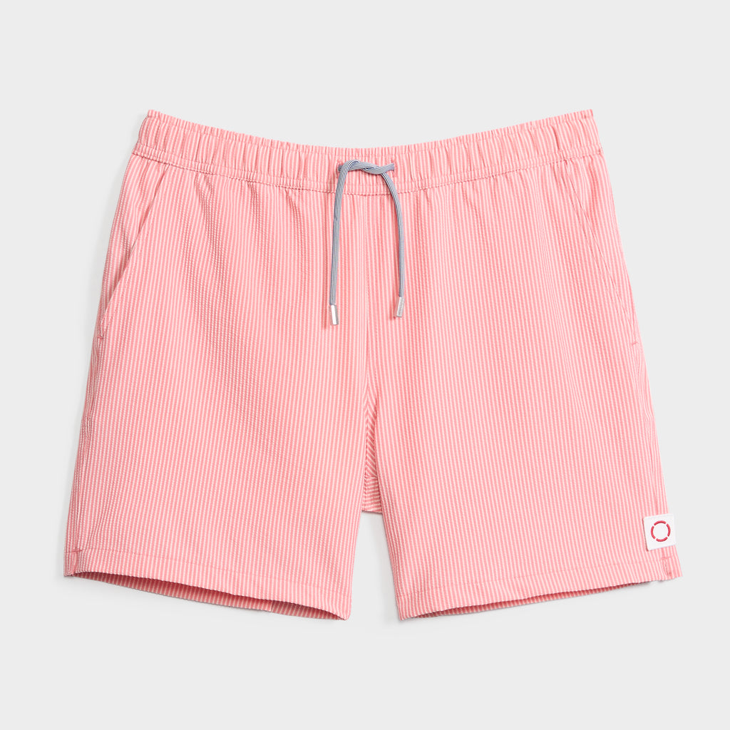 SAINT TROPEZ men’s swim shorts by PUBLIC BEACH SWIM feature pink and white thin stripes, an elastic waistband with a gray drawstring, and a white patch with a red circle—quick-dry trunks for stylish beachwear. Shown on a light gray background.
