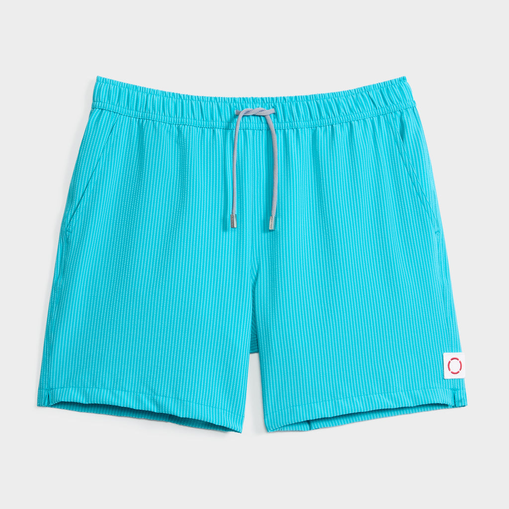 SAINT TROPEZ men's swim shorts by PUBLIC BEACH SWIM: turquoise with thin white stripes, elastic waistband, grey drawstring, and a white patch with a red circle—stylish quick-dry beachwear photographed on a crisp white background.