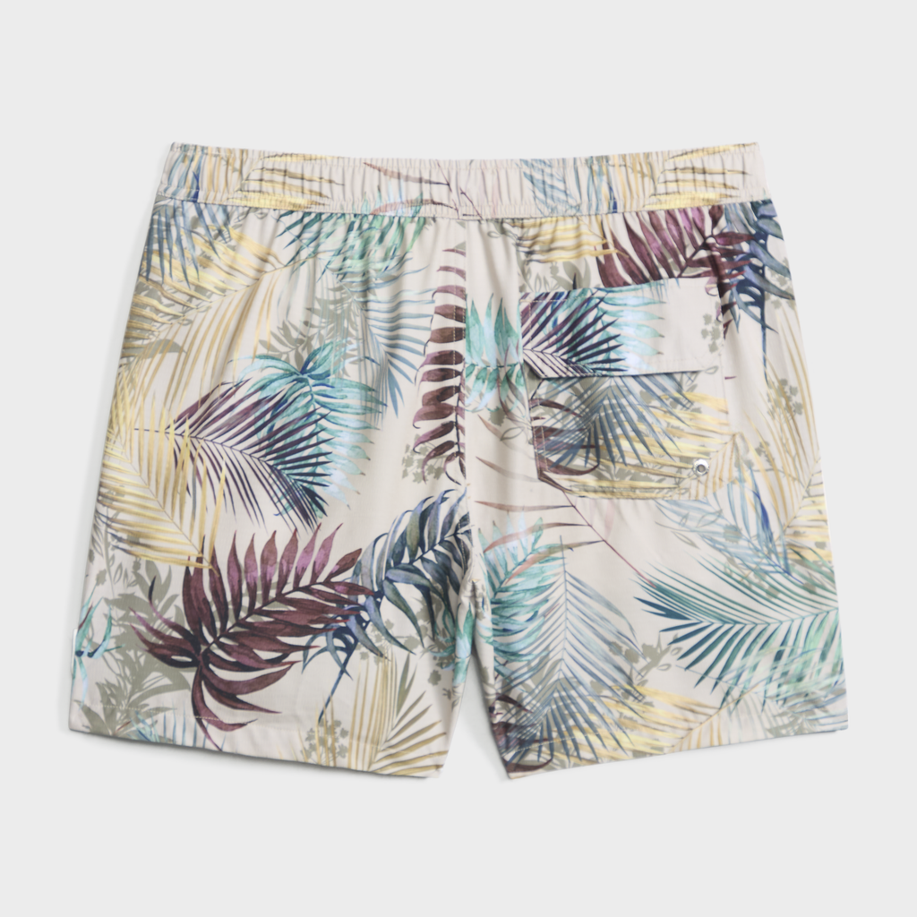 The BOTANIC BURST swim trunk by PUBLIC BEACH SWIM showcases a vibrant tropical leaf print, elastic waistband, quick-dry fabric, and a buttoned back pocket for style and comfort.