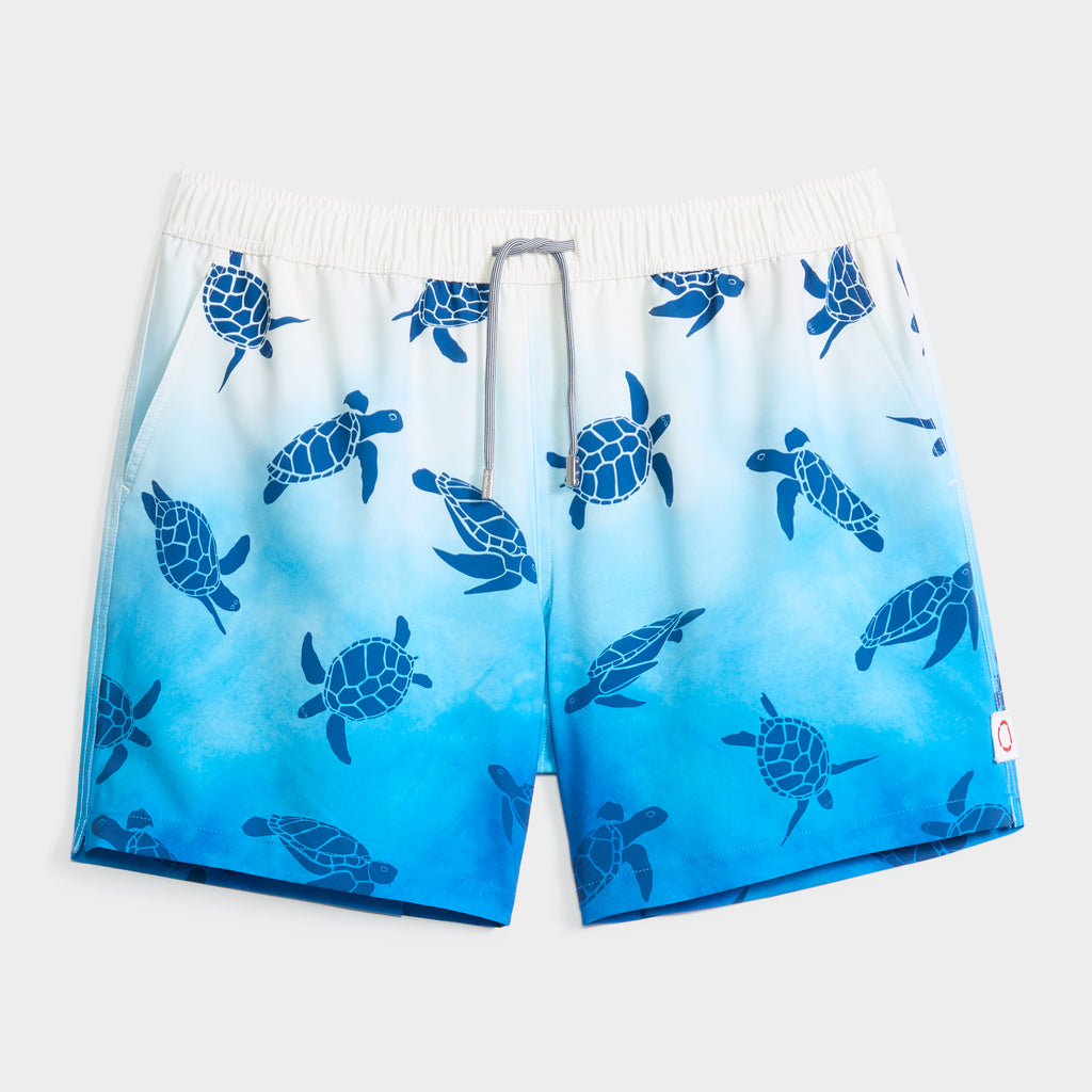 The PUBLIC BEACH SWIM TURTLE WAVES men's swim short features a blue and white sea turtle pattern, quick-dry fabric, elastic waistband with gray drawstring, compression liner, and a red and white logo tag on the lower left.