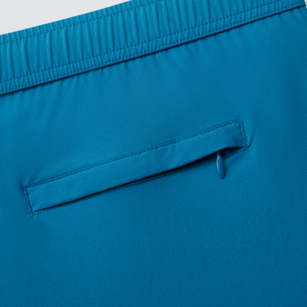 Close-up of THE VINTAGE men's swim shorts by PUBLIC BEACH SWIM in blue, featuring an elastic waistband and a horizontal back pocket with a flap and pull tab—blending classic beachwear and vintage styling.