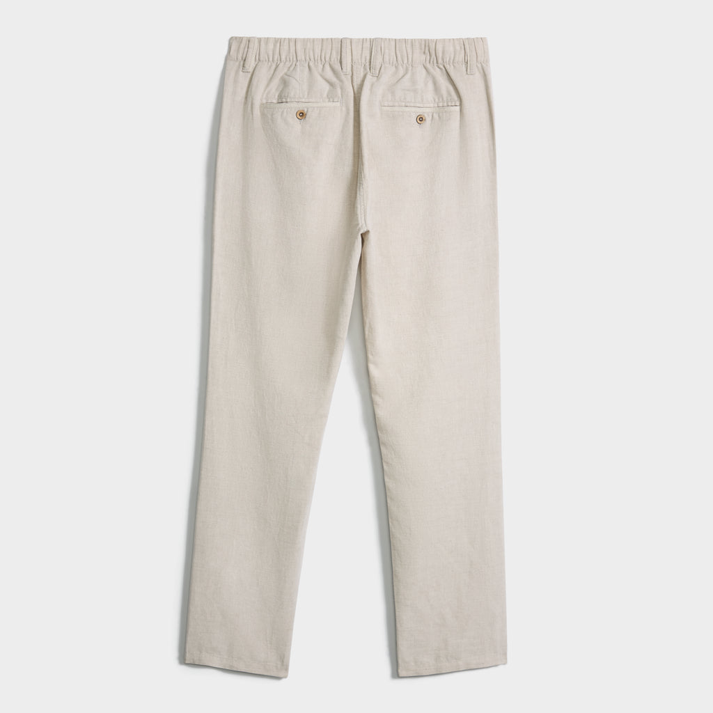 The LINEN BLEND PANTS by PUBLIC BEACH SWIM feature a beige linen-cotton blend, elastic waistband, straight legs, and two buttoned back pockets, shown laid flat on a white background. Breathable fabric ensures all-day comfort.